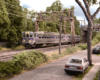 A silver two-car electric SEPTA commuter train glides under an overpass by a residential street