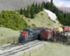 A gray-and-scarlet diesel with a manifest train passes by a stock pen in the mountains