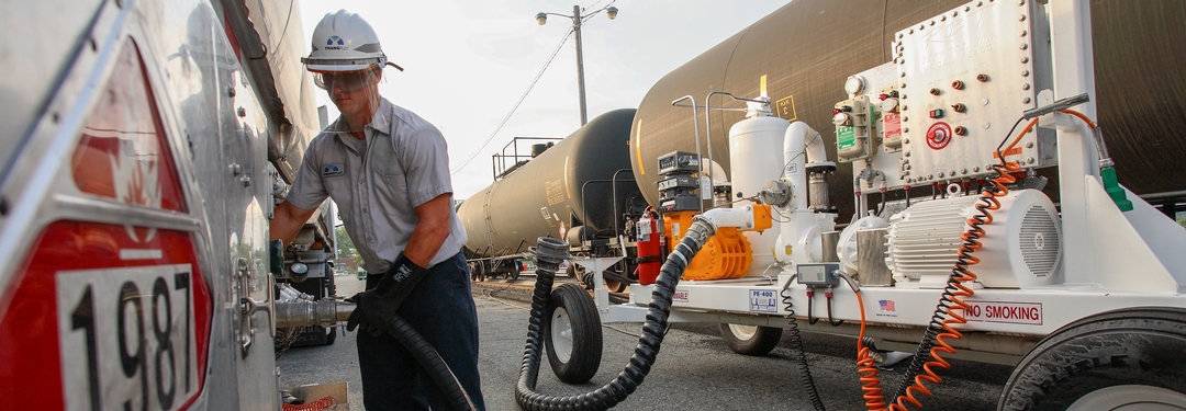 Man transfers chemicals from tank car to tanker truck