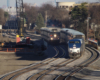 Amtrak passenger train passes Metra commuter train in view from bridge across tracks.