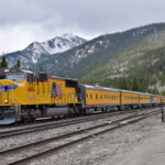 Yellow locomotive and passenger cars at tunnel.