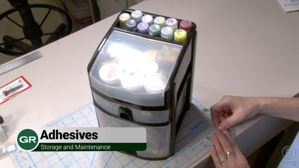 Hands next to a plastic container of adhesives