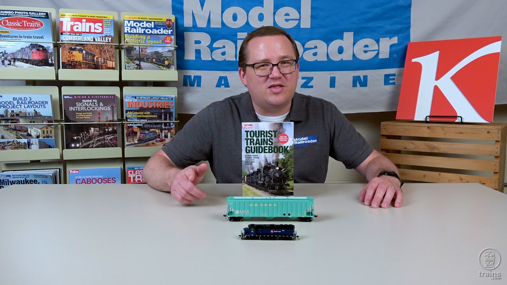 Cody Grivno sitting with two train products and a book