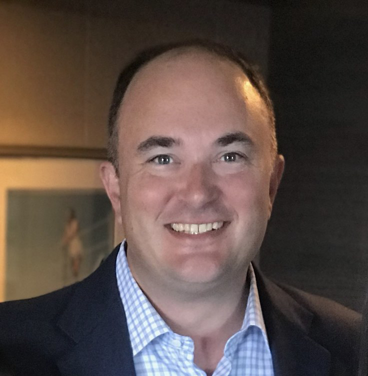 Smiling man in coat and open-collared shirt