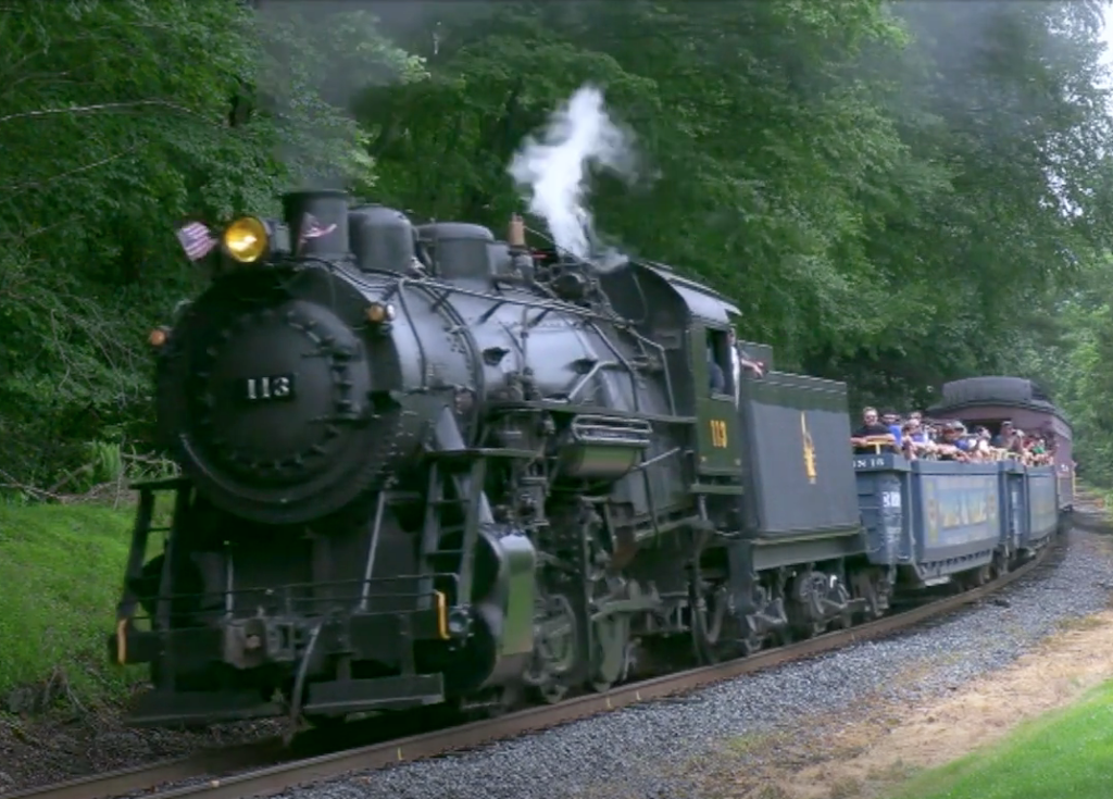 A steam locomotive hauling excursion train with passengers.