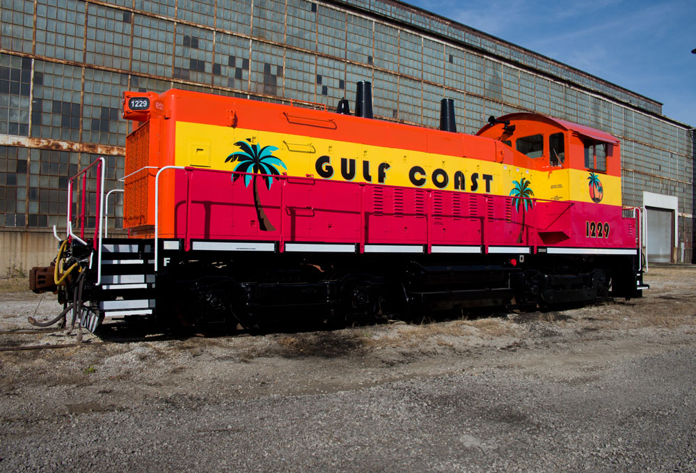 red, yellow, and palm trees on locomotive sitting on tracks