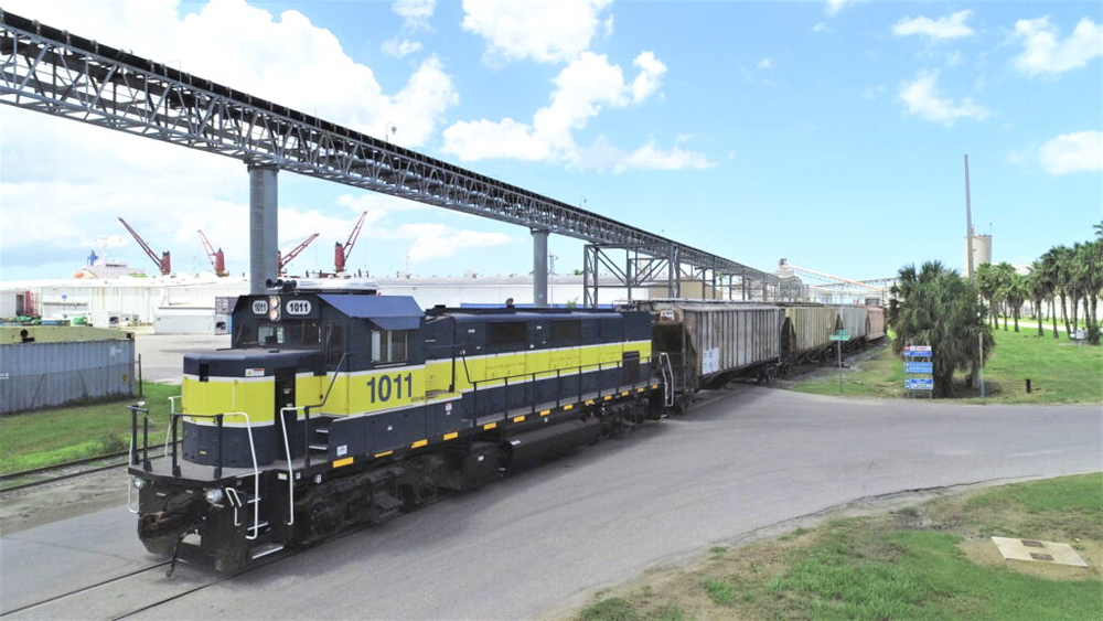 Blue and yellow genset locomotive with freight cars