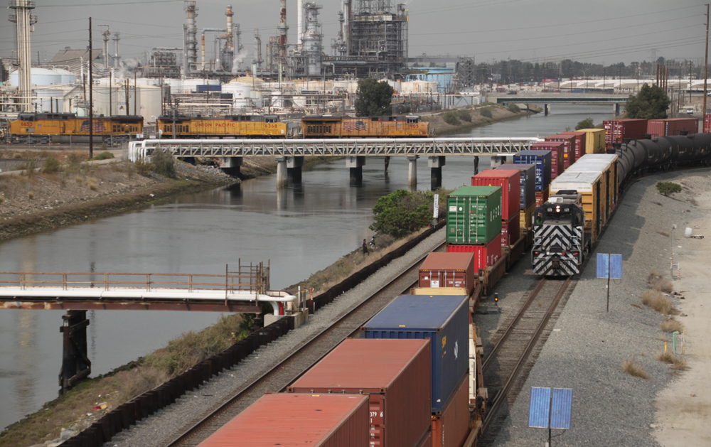 Two trains meet along river while another crosses water on bridge