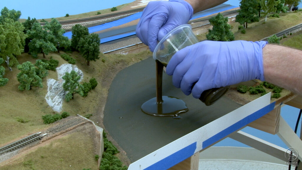 David is pouring two-part resin in to the river basin on the State Line Route project railroad