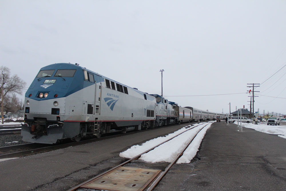 blue and silver locomotive with its passenger cars on dreary day