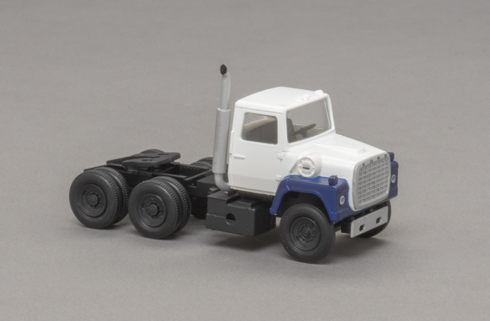 Photo of HO scale tractor with white cab, blue fenders, and black fuel tank and chassis.