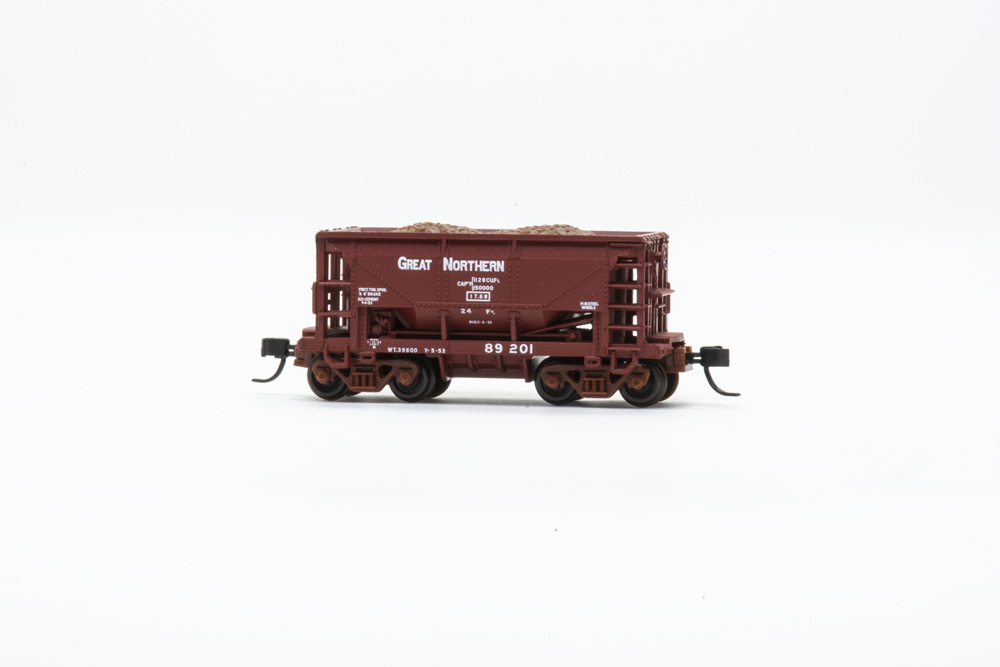 Photo of N scale ore car painted brown with white lettering and ore load on white background.