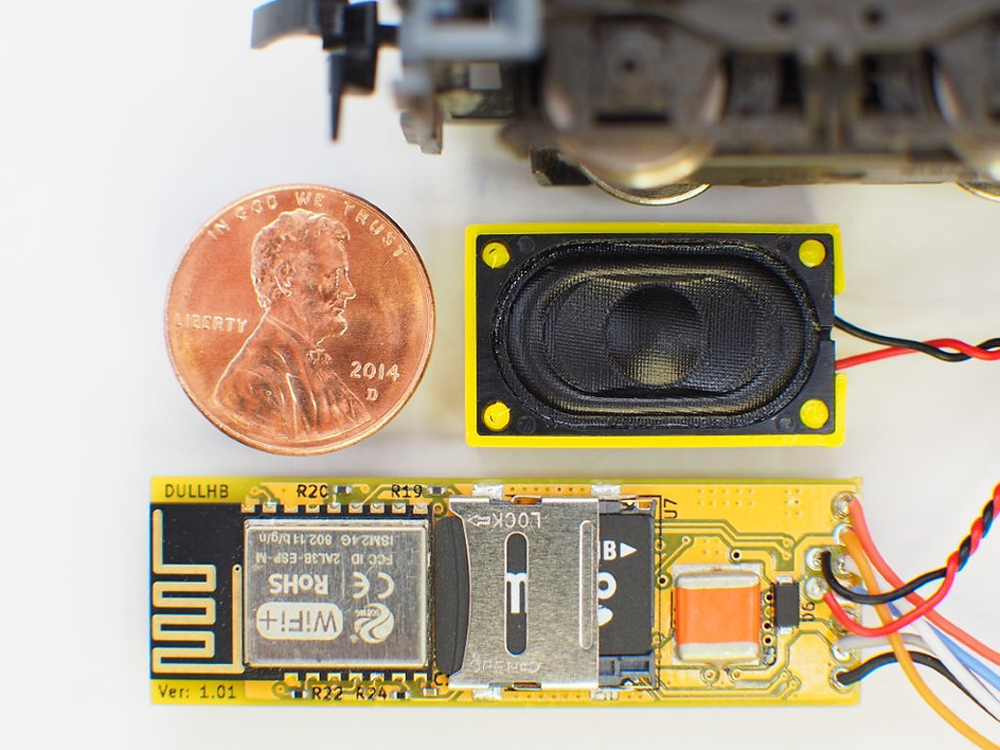 Photo of sound decoder and speaker with U.S. penny next to speaker for size reference.