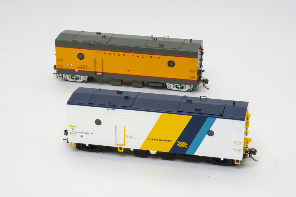 Photo of two HO scale steam heater cars, one painted yellow, red, and gray and the other white, blue, and yellow, on white background.