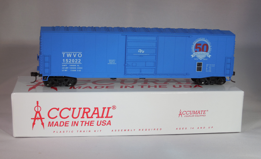 Photo of blue HO scale 50-foot boxcar on top of red-and-white kit box.