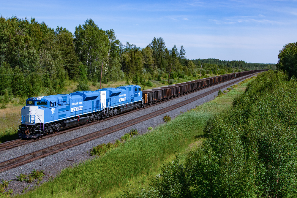 Blue and white locomotives with train of ore cars