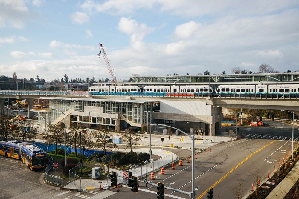 Light rail train at elevated station with construction equipment