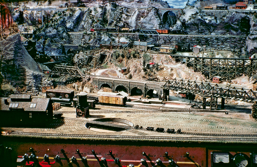 : An HO scale locomotive servicing area is surrounded by high bridges, cliffs, and mountains.