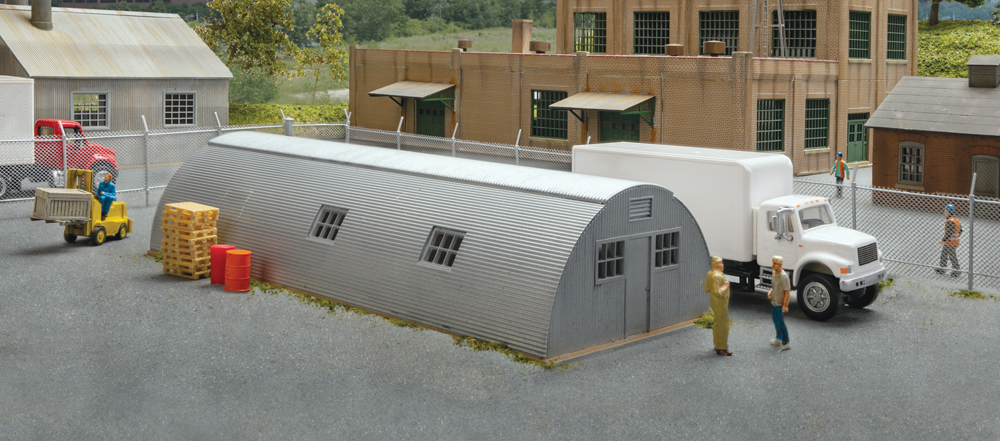 Photo of assembled and painted HO scale Quonset hut in a scene with vehicles, figures, and details.