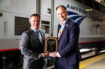 Two men on station platform with Amtrak locomotive in background