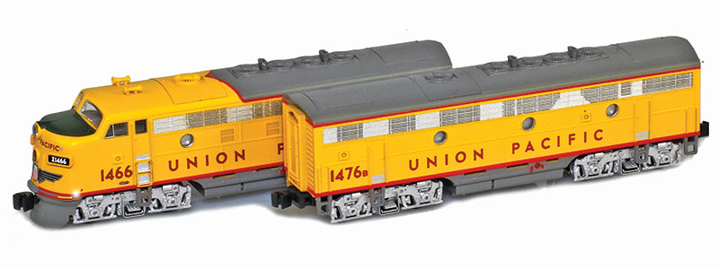 Photo of Z scale Electro-Motive Division F7A and F7B diesel locomotives painted yellow and gray with red graphics and silver trucks on white background. 