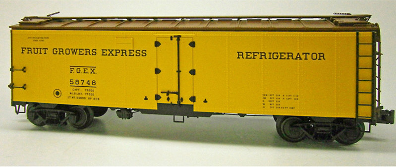 O scale refrigerator car painted yellow, brown, and black.
