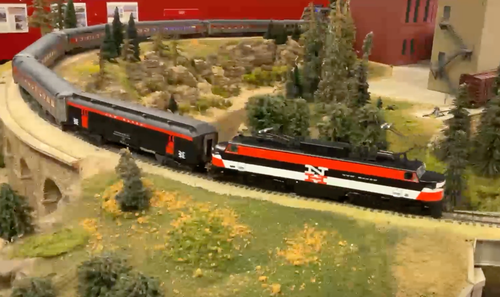 Orange, black, and white painted passenger train on a curve.