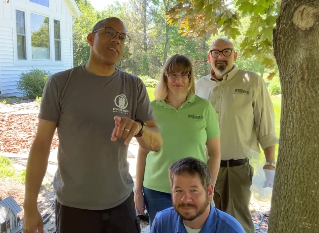 Four people posing in front of a camera outdoors.