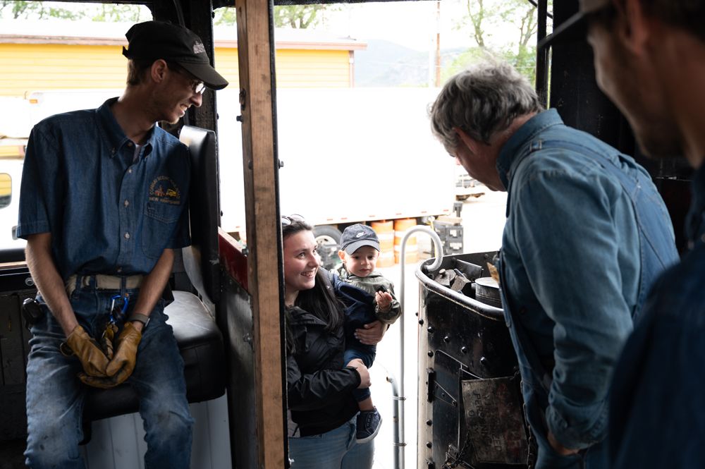 Woman holding young boy as he looks into cab of steam locomotive