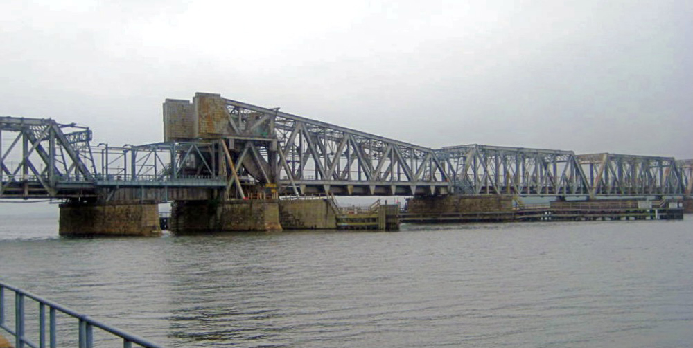 Steel bridge across river under gray skies