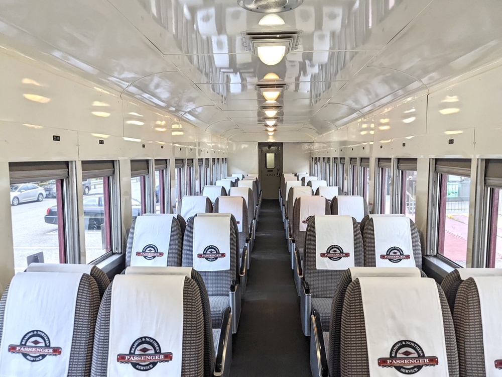 Interior of passenger car with cream-paint and four-across coach seats