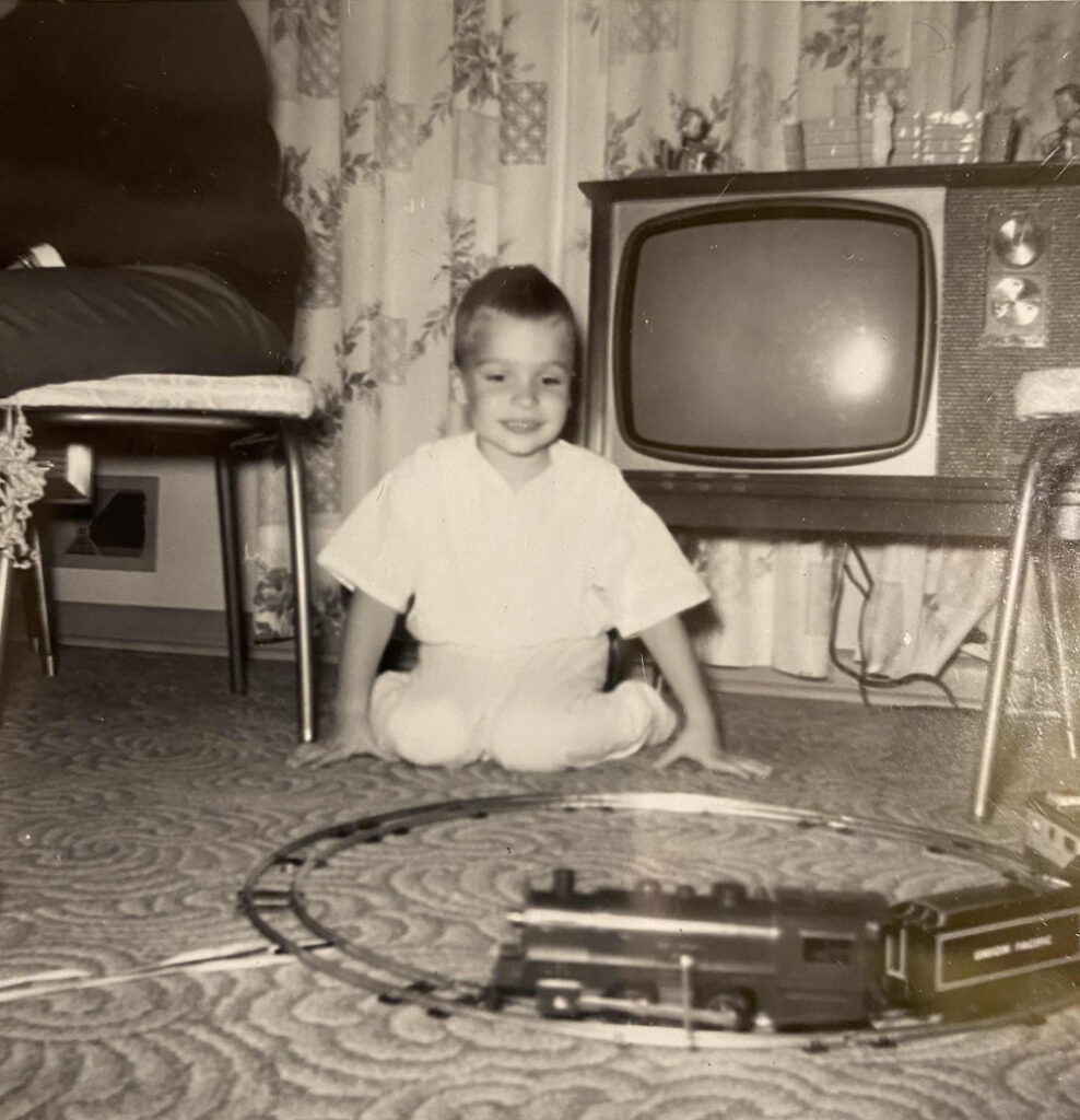 black and white photo of young boy with train set