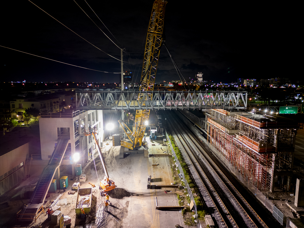 Night view of bridge being lowered in to place by crane