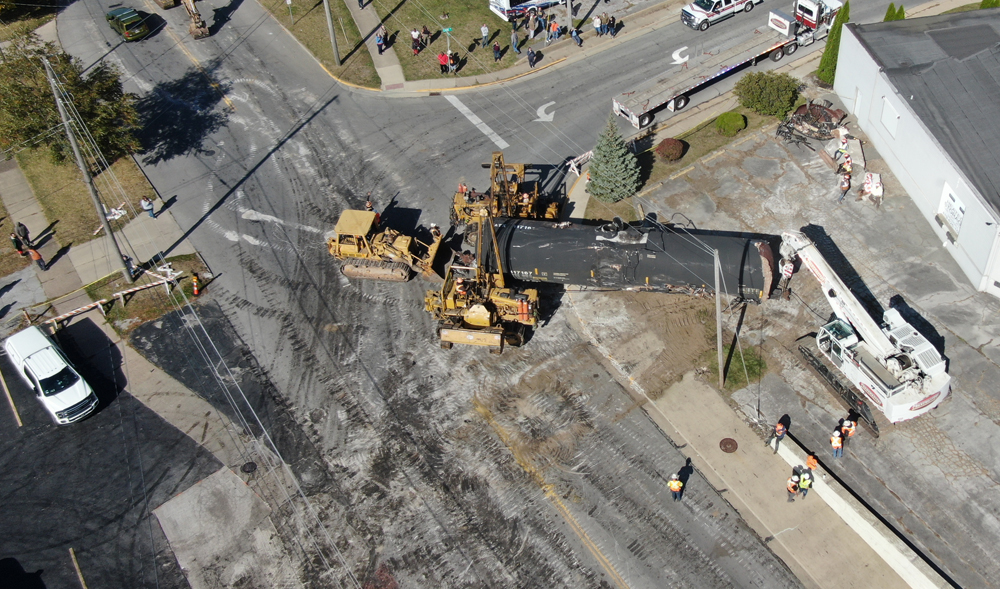 Aerial view of damaged tank car being moved by heavy equipment