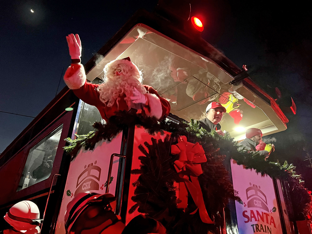 Man in Santa suit waves from platform at back of passenger car