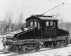 Black centercab electric locomotive with trolley pole raised