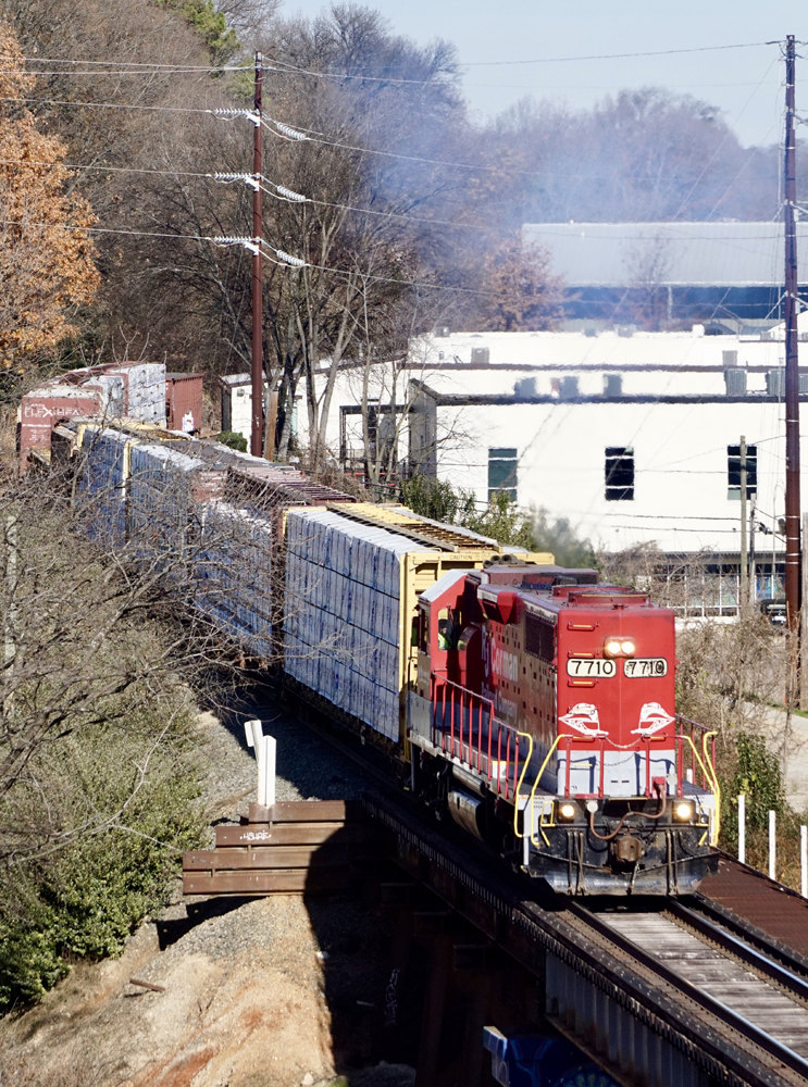 Train with red and white locomotive approaches bridge