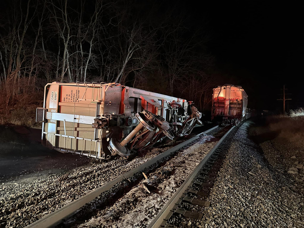 Auto rack on side at derailment scene at night