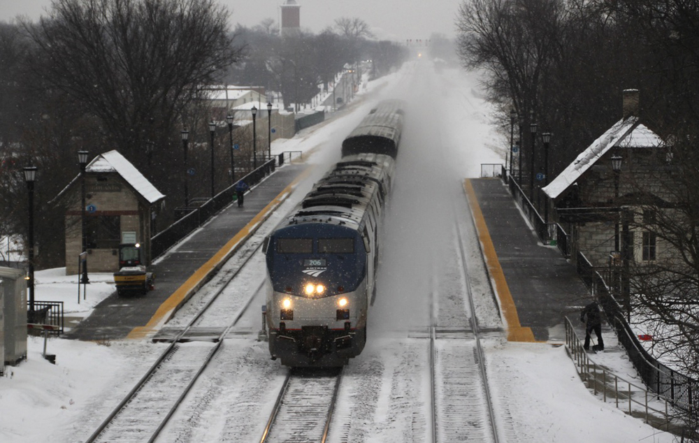 Passenger train on middle of three tracks during snowfall