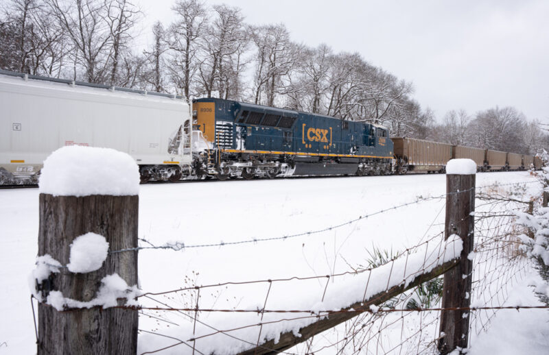 blue and gold locomotive on track with snow