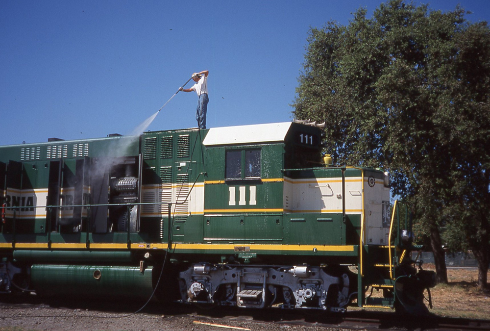 green and white locomotive being washed