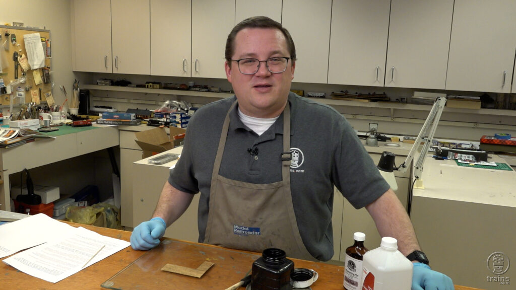 wood stains for modeling: A man standing behind a work bench wearing an apron