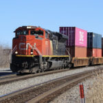 Intermodal train with one red and black locomotive on curve