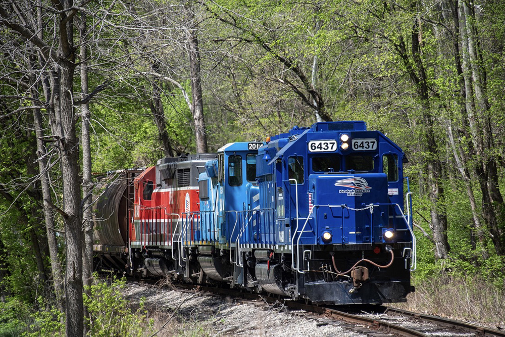 Three locomotives in three paint schemes bring a train around a cruve
