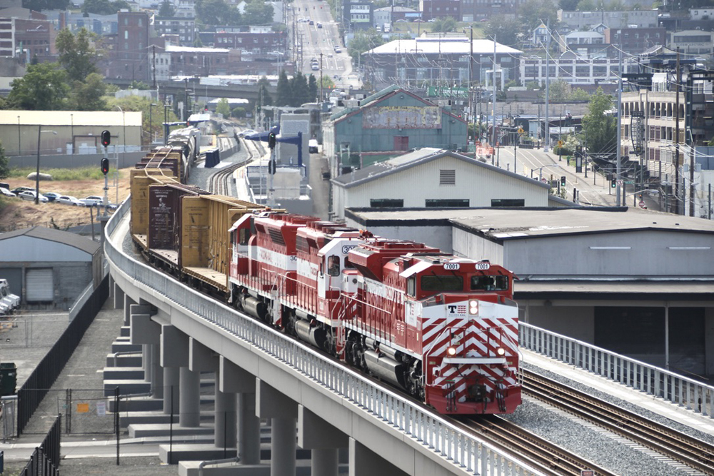 Red and white locomotives lead freight train on long bridge