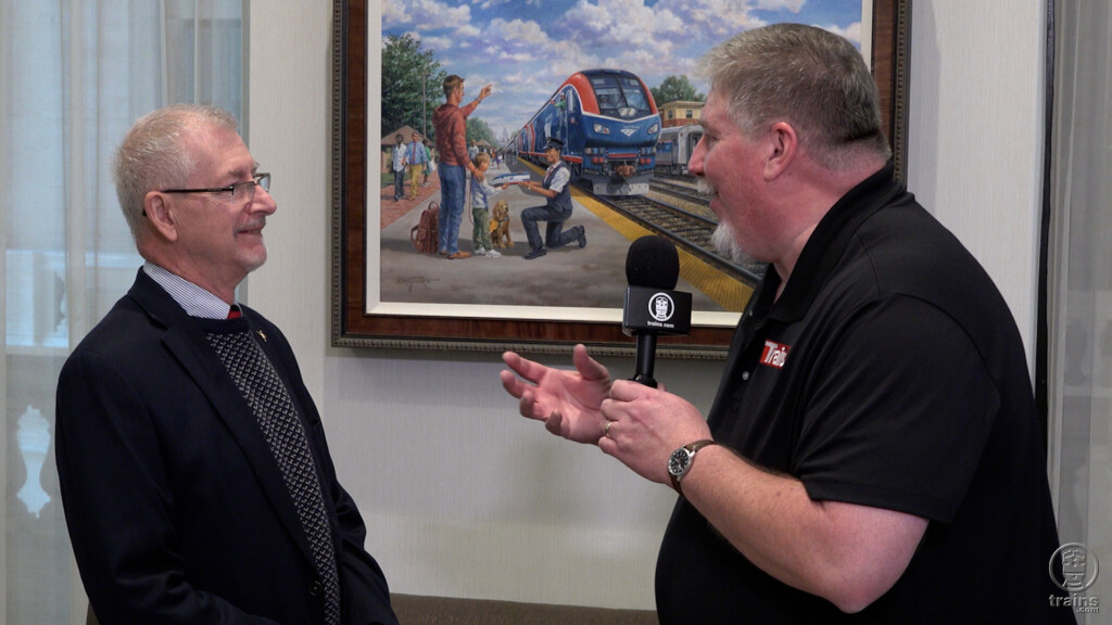 Two men standing in front of a passenger train painting. Trains LIVE — Railroad artist J Craig Thorpe