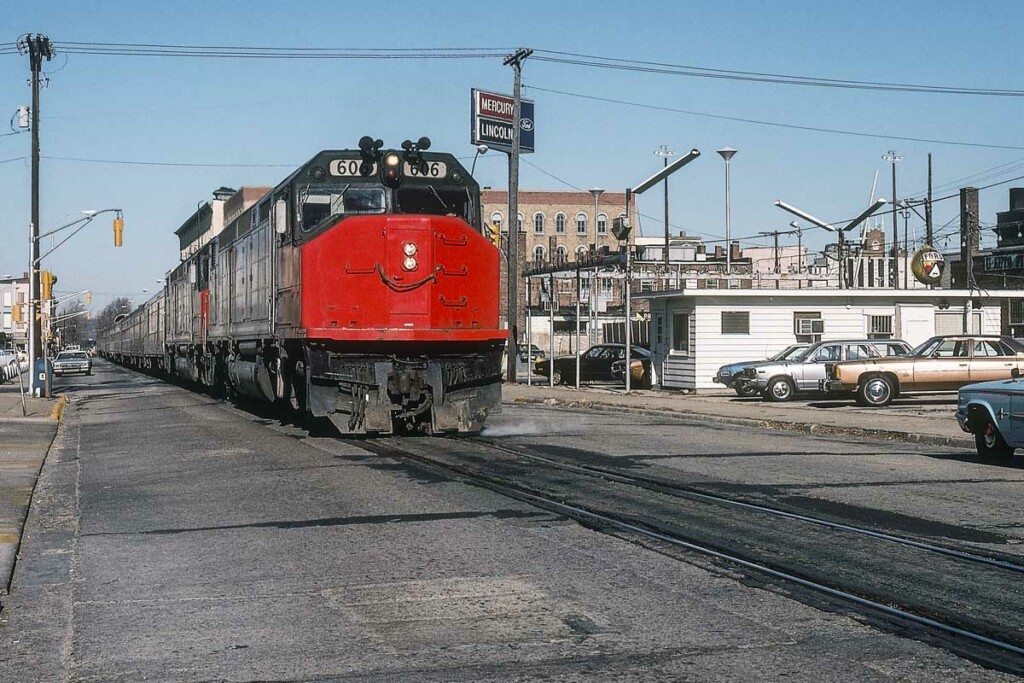 Red-and-black diesel locomotive with Amtrak Floridian passenger train in street