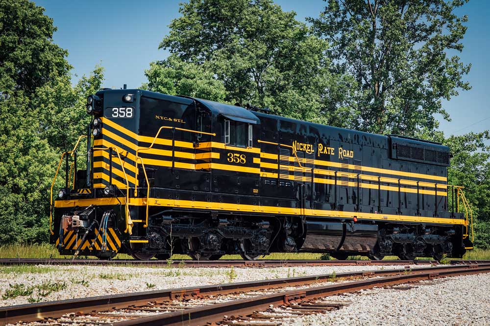 Black-and-yellow Nickel Plate Road diesel locomotive in front of trees