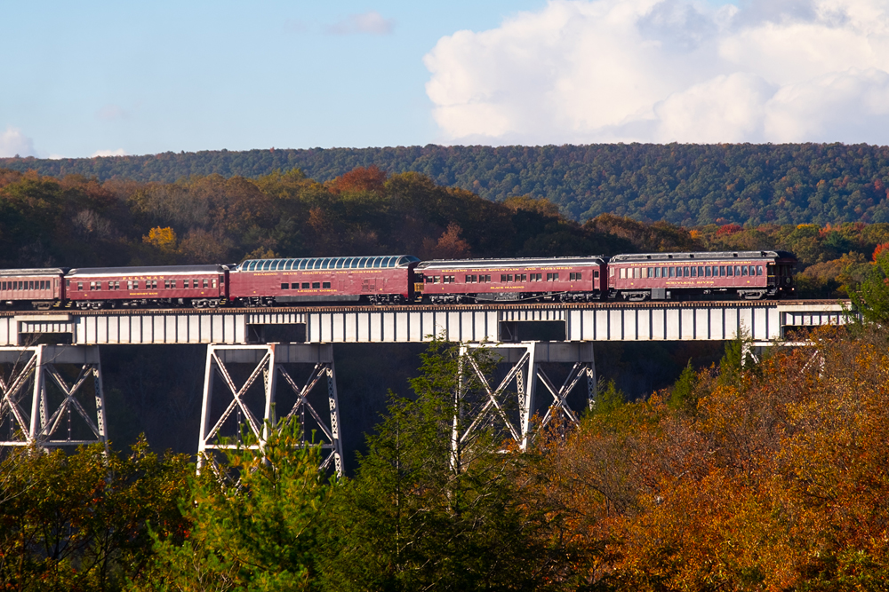 red train going over bridge in fall