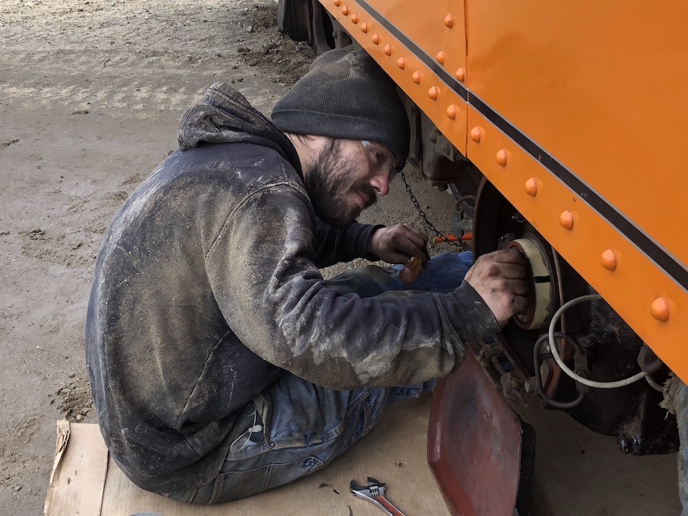 Young worker performing repair work on an interurban car.